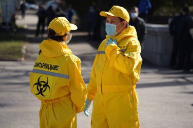 Almaty, Kazakistan - 03.27.2021: Özel takım elbiseli sağlık görevlileri şehirde devriye geziyor