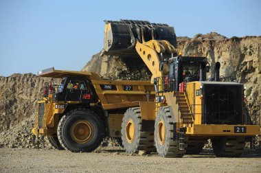 East Kazakhstan region, Kazakhstan - 12.02.2015 : Mining and unloading of copper ore in the quarry with the help of special equipment. clipart