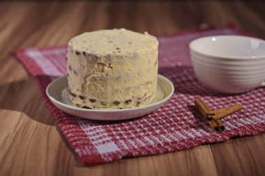 A buttercream cake and a cup of coffee with cinnamon sticks.