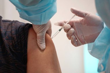 Almaty, Kazakistan - 08.11.2021: Doktor hastaya aşı yapar ve enjekte eder.