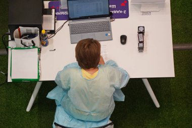 Almaty, Kazakistan - 08.11.2021: Doktor aşı merkezinde masada oturuyor