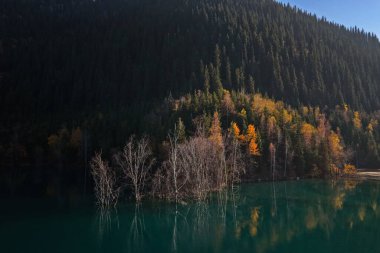 Issyk Gölü batan güneşin ışınlarında. Ulusal Doğa Parkı. Farklı bitki örtüsü olan dağlık bir bölge. Bir İHA görüntüsü.