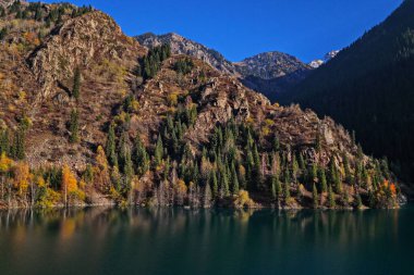 Issyk Gölü batan güneşin ışınlarında. Ulusal Doğa Parkı. Farklı bitki örtüsü olan dağlık bir bölge. Bir İHA görüntüsü.