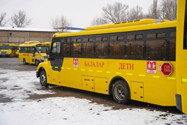 Almaty, Kazakistan - 12.18.2025: Sarı okul otobüsleri için park yeri. Kış zamanı, kar yağışı.