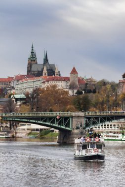 PRAGUE, CZECH REPUBLIC - 4 Kasım 2012: Çehov Köprüsü yakınlarındaki Vltava 'da küçük bir tekne, Prag Kalesi, sonbahar bulutlu günü