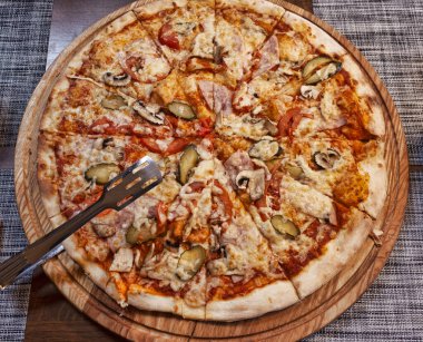 Salamlı, mantarlı, salatalıklı, domatesli ve peynirli büyük boy pizza.