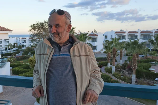 Deniz kenarındaki otel balkonunda çekici olgun bir adamın portresi.
