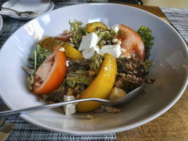 Domatesli sebze salatası, fırında dolmalık biber, peynir ve hindi eti parçaları, marul yapraklarıyla süslenmiş ve kimyon serpiştirilmiş.