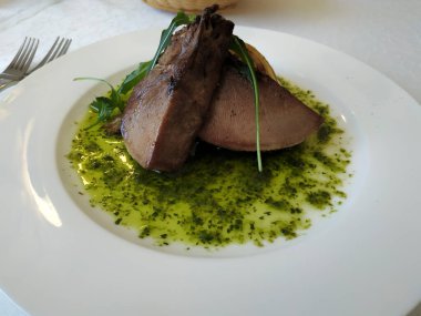 Baharatlı ekşi soslu ızgara lahana ile ızgara dil. Geniş beyaz tabakta servis edilir.