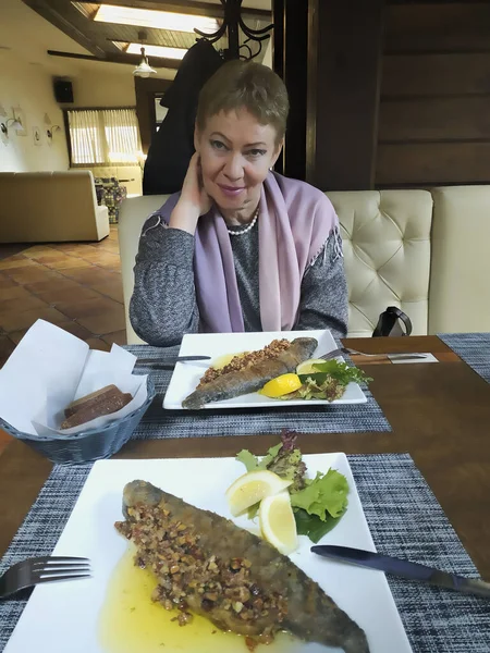 Mogen Kvinna Vid Ett Bord Restaurang Bordet Står Maträtt Öring — Stockfoto