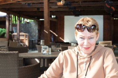 Parkta, bir yaz kafeteryasının masasında, olgun bir kadın.