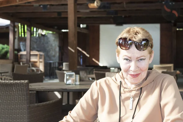 Parkta, bir yaz kafeteryasının masasında, olgun bir kadın.