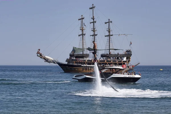 Flyboard και την ιστιοπλοΐα στυλιζαρισμένη πειρατική σκούνα — Φωτογραφία Αρχείου