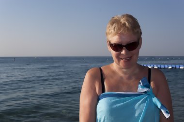 Orta yaşlı kadın bir pareo ve güneş gözlüğü