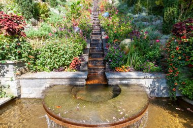 Teraslı çiçek bahçeleri ve Mainau Adası 'ndaki yuvarlak bir havuza taştan bir şelale şelalesi, güneşli bir günde bereketli Akdeniz tarzı bitki örtüsü sergiliyor. Konstanz, Almanya