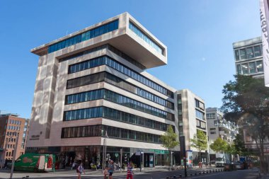 HAMBURG, GERMANY - 12 AĞUSTOS 2024: Hamburg 'daki Hollanda-Amerika Lijn' in belirgin, modern ofis binası, temiz hatlar, geniş pencereler ve berrak mavi gökyüzüne karşı döşenmiş çatı yapısı
