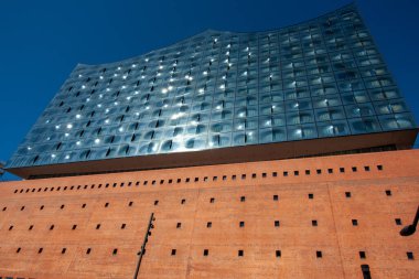 HAMBURG, GERMANY - 12 Ağustos 2024: Hamburg, Almanya 'daki ikonik Elbphilharmonie konser salonu, büyük tuğla temeli ile yukarıdaki eğimli cam yapı arasındaki dramatik zıtlığı gözler önüne seriyordu.