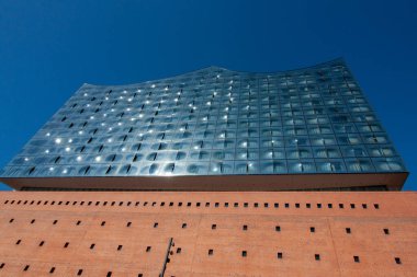 HAMBURG, GERMANY - 12 Ağustos 2024: Hamburg, Almanya 'daki ikonik Elbphilharmonie konser salonu, büyük tuğla temeli ile yukarıdaki eğimli cam yapı arasındaki dramatik zıtlığı gözler önüne seriyordu.