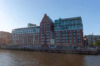 HAMBURG, GERMANY - 12 Ağustos 2024: Hamburg Elbe Nehri 'ndeki konut ve ofis binaları. Kırmızı tuğla depo tarzı mimari ve balkonlu modern cam cephelerin karışımı.