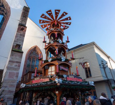 BASEL, SWitzERLAND - 16 Aralık 2024: Geleneksel bir Alman ahşap Noel piramidinin mumlar ve heykelciklerle aydınlatılmış ve Basel Noel Pazarı 'nda popüler bir tezgah olarak hizmet veren ayrıntılı bir yakın çekimi