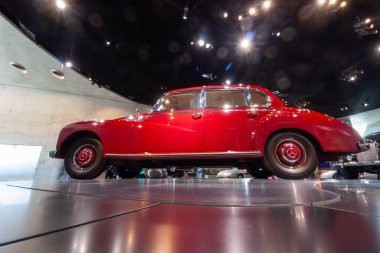 STUTTGART, GERMANY - OCTOBER 18, 2025: Side view from a low angle of a majestic red 1950s Mercedes-Benz 300 Adenauer sedan at the Mercedes-Benz Museum