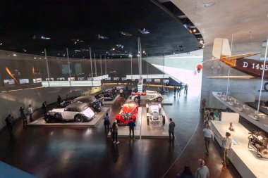 STUTTGART, ALMANY - 18 Ekim 2025: Mercedes-Benz Müzesi 'nin ikonik klasik arabalar, ziyaretçiler ve parlak ışıklar altında tarihi bir uçak kuyruğu bölümü
