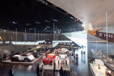STUTTGART, ALMANY - 18 Ekim 2025: Mercedes-Benz Müzesi 'nin ikonik klasik arabalar, ziyaretçiler ve parlak ışıklar altında tarihi bir uçak kuyruğu bölümü