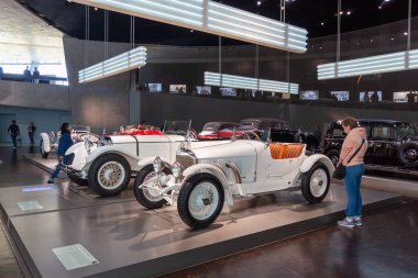 STUTTGART, GERMANY - 18 Ekim 2025: Modern bir müze salonunda ziyaretçi ve profesyonel ışıklandırmayla sergilenen çeşitli klasik arabaların geniş görünümü, otomotiv evrimini gözler önüne seriyor
