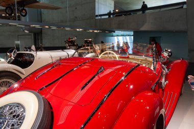 STUTTGART, GERMANY - 18 Ekim 2025: Yedek lastiği ve arka planında antika bir uçakla modern bir müzede sergilenmekte olan lüks kırmızı bir klasik arabanın arka görüntüsü