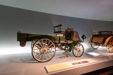 STUTTGART, GERMANY - OCTOBER 18, 2025: Early Daimler motor vehicle from 1899 at the Mercedes-Benz Museum. Historical transition from horse carriage to motorized transportation
