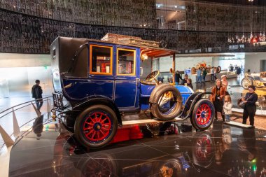 STUTTGART, GERMANY - OCTOBER 18, 2025: Vintage blue luxury car with red wheels on display at the Mercedes-Benz Museum. Historical automobile exhibition in a modern museum hall with visitors