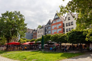 COLOGNE, GERMANY - 31 Mayıs 2024: Açık kafeli renkli geleneksel ve modern binalar ve Ren nehri boyunca uzanan kırmızı şemsiyeler
