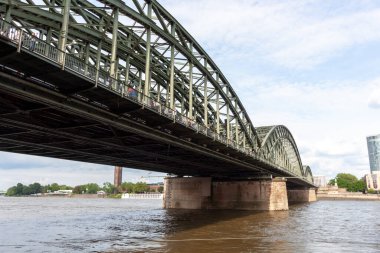Almanya, Köln 'de yürüyen yayalarla Ren Nehri' ni kaplayan Hohenzollern Köprüsü 'nün geniş çelik kemerlerinin alçak açılı görüntüsü