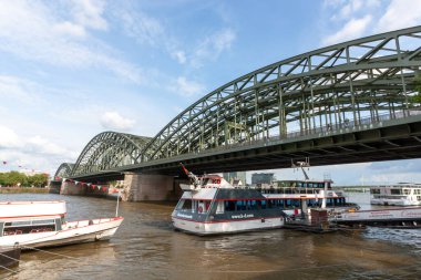 COLOGNE, ALMANY - 31 Mayıs 2024: Ren nehrine yanaşan bir yolcu gemisi Köln, Almanya 'daki Hohenzollern Köprüsü' nün çelik kemerlerinin yanına yanaştı