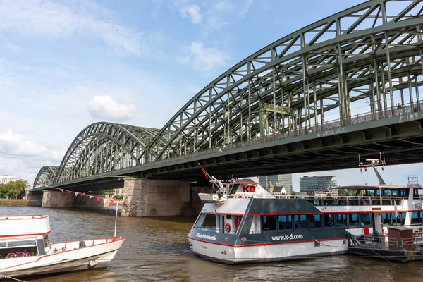 COLOGNE, ALMANY - 31 Mayıs 2024: Ren nehrine yanaşan bir yolcu gemisi Köln, Almanya 'daki Hohenzollern Köprüsü' nün çelik kemerlerinin yanına yanaştı