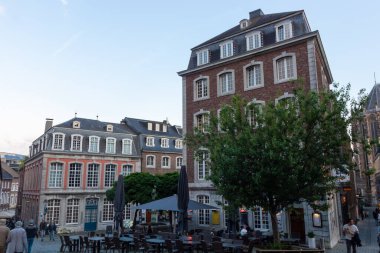 AACHEN, ALMANY - 31 Mayıs 2024: Almanya 'nın Aachen kentindeki tarihi tuğla binalar. Parke taşlı bir meydanda açık havada oturan rahat bir sokak kafesi. Geleneksel Avrupa mimarisi ve şehir atmosferi