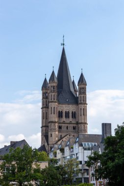 COLOGNE, GERMANY - 31 Mayıs 2024: Büyük St. Martin Kilisesi 'nin Roma kulesi Almanya' nın eski Köln kentindeki yerleşim binalarının üzerinde yükseliyor. Mavi gökyüzünün altında tarihi mimari simgeler