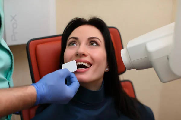 Bir dişçi intraoral kalkan kadın hasta ağız ve x-ışını yönlendirerek Yardımcısı koyarak kapatın — Stok fotoğraf