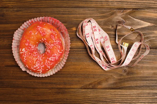 Пончик и скотч на доске, представляющие сладкое злоупотребление сахаром и зависимость равны лишнему весу тела и нездоровому питанию в концептуальном образе — стоковое фото