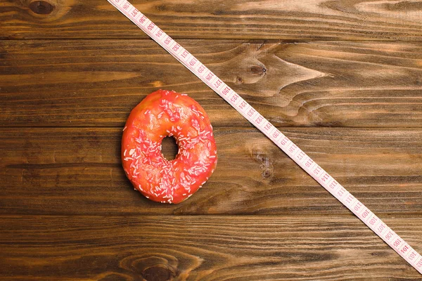 donut and tailor measure tape on blackboard representing sugar sweet abuse and addiction equal body overweight and unhealthy nutrition in conceptual image