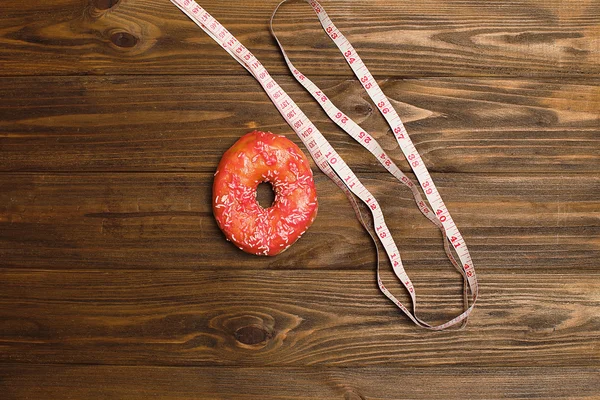 Пончик и скотч на доске, представляющие сладкое злоупотребление сахаром и зависимость равны лишнему весу тела и нездоровому питанию в концептуальном образе — стоковое фото