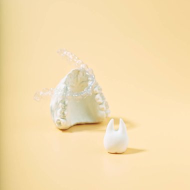 Sarı arka planda ortodontik diş teması. Ortodontik diş tedavisi için kullanılabilir şeffaf görünmez diş hizalayıcılar veya diş telleri