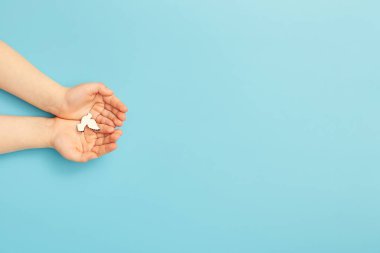 Child hands holding white dove bird on blue background, international day of peace or world peace day concept.