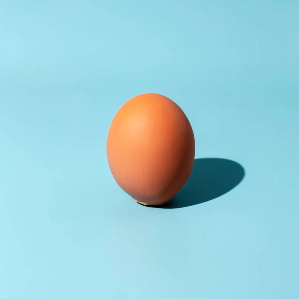 Egg over blue background. Sunshine with hard shadow. Minimal food concept