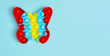 Moda oyuncağı anti-stres. Renkli poppit oyunu olan isimsiz bir çocuk. Modayı takip eden popüler oyuncağın görüntüsü. Yeni duyusal oyuncağın üst görünümü