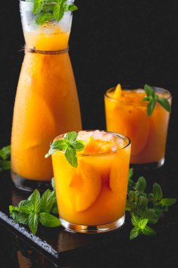 Summer cold drinks: homemade peach sangria with ice , and mint in glass on black background.	