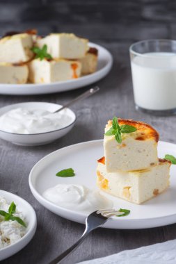 Cottage cheese casserole with raisins and cup of milk on wooden grey background. Cottage cheese casserole.	