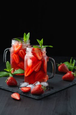 Taze çilek kokteyli. Çilekli ve buzlu taze yaz kokteyli. Koyu arkaplanda bir bardak çilekli soda..