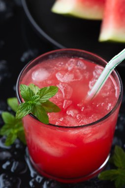 Karpuzlu soğuk bir yaz içeceği ve siyah ahşap bir arka planda nane.