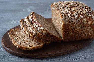 Kesme tahtasında dilimlenmiş çavdar ekmeği. Tohumlu tam tahıllı çavdar ekmeği.